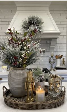 a christmas arrangement in a kitchen with candles and decorations on the counter top, surrounded by greenery