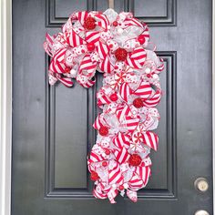 a red and white wreath with candy canes hanging on the front door for christmas