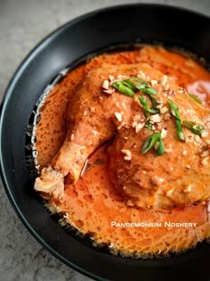 a black bowl filled with meat covered in sauce