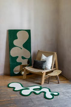 a wooden chair sitting next to a green and white painting