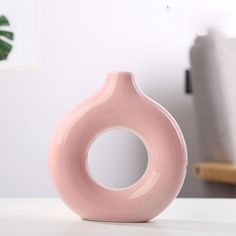 a pink vase sitting on top of a white table