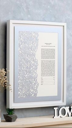 a white framed paper with the words love written in it on top of a shelf