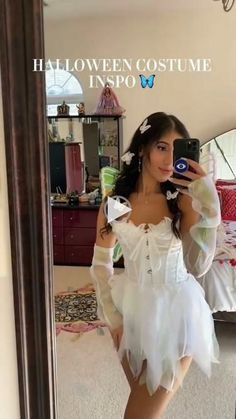 a woman taking a selfie in front of a mirror wearing a white halloween costume