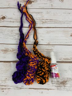 the crochet is being used to make an orange, purple and black scarf