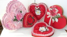 four heart shaped boxes with flowers and hearts on the front, one in red and one in pink