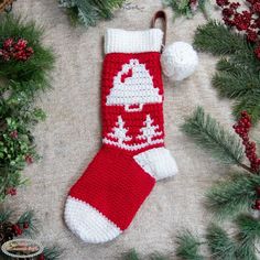 a knitted christmas stocking laying on top of a carpet next to pine branches