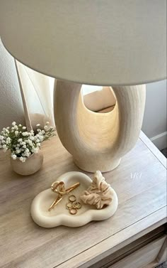 a white lamp sitting on top of a wooden table next to a vase with flowers