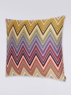 a multicolored pillow on a white background with an orange and yellow zigzag pattern