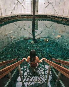 a woman sitting on top of a glass floor in front of a large aquarium tank