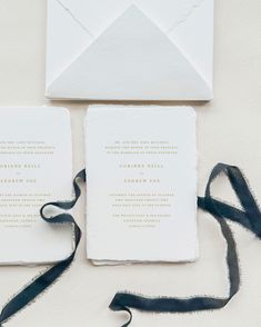 the wedding stationery is laid out on top of an envelope and tied with black ribbon