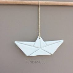 a white origami boat hanging on a wall