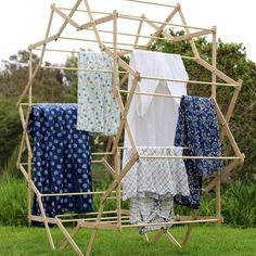 clothes hanging on a clothes rack in the grass with blue and white towels hung from it