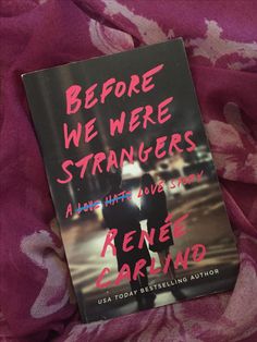 the book before we were strangers is laying on top of a pink flowered blanket