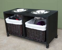 two dog bowls sitting on top of a wooden stand with baskets underneath it and one is empty