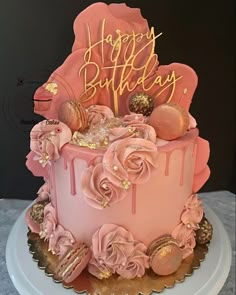 a birthday cake with pink frosting and gold decorations