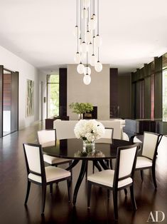 a dining room table with white chairs and a chandelier hanging from the ceiling