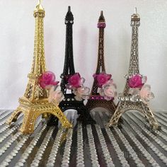 three miniature eiffel tower with pink roses in the middle and two smaller ones on top