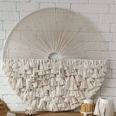 a white wall hanging on the side of a brick wall next to a basket and hat