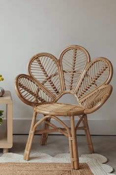 a wicker chair sitting on top of a rug next to a vase with flowers