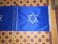 two blue flags with the star of david on them are sitting on a tiled floor