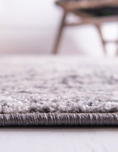 a close up view of a rug on the floor with a chair in the background