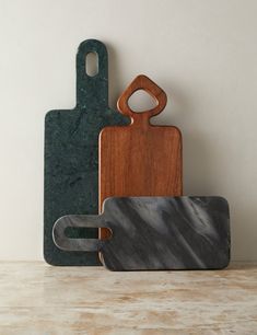 three wooden cutting boards sitting next to each other on top of a marble countertop