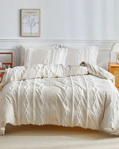 a bed with white comforter and pillows in a bedroom next to a nightstand on the floor