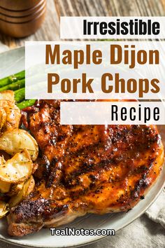 a white plate topped with pork chops next to potatoes and asparagus on a wooden table