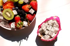 a fruit salad in a bowl next to a cut up dragon fruit