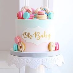 a baby shower cake with donuts and macaroons on the top, decorated in pastel colors