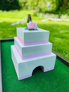 a three tiered cake sitting on top of a green table covered in fake grass