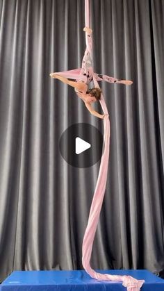 a woman is doing tricks on a pole in front of a curtain with her hands