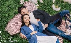 two people laying in the grass with their arms around each other and one person sleeping