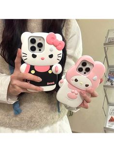 a woman holding two cell phones with hello kitty cases on their faces and one is holding a cat