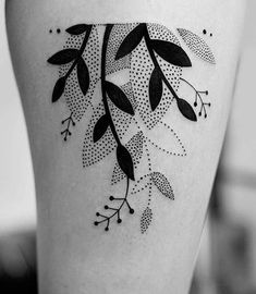 a black and white photo of a woman's thigh with leaves on it