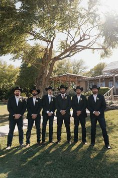 a group of men standing next to each other in front of a tree