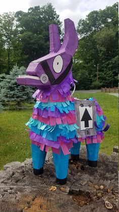 a purple and blue animal statue sitting on top of a tree stump