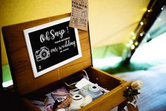 an open wooden box filled with items on top of a floor next to a sign