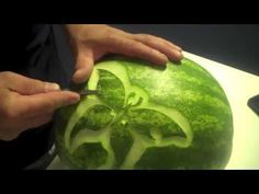 someone carving a watermelon in the shape of a flower