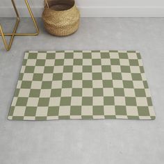 a green and white checkered rug on the floor next to a basket with a plant in it