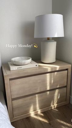 a white lamp sitting on top of a wooden dresser