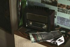 an old radio sitting on top of a wooden table next to a wall with pictures