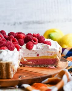 a piece of cake with raspberries and whipped cream is on a cutting board