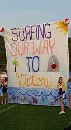 a sign that says surfing our way to victory on the side of a football field