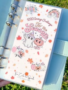 a hand holding a planner book with stickers on the cover and writing in it