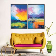 two paintings on the wall above a couch in a room with a table and vase