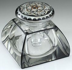 a clear glass jar with a flower design on it's lid, sitting on a white surface