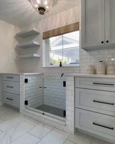 a kitchen with white cabinets and tile flooring in the center, along with a chandelier hanging from the ceiling