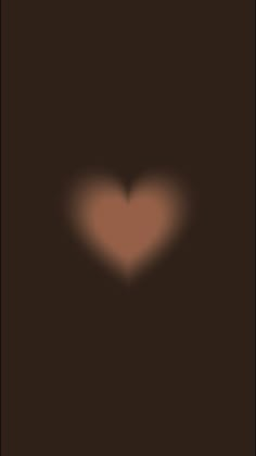 a blurry image of a heart on a dark background with the light shining through it