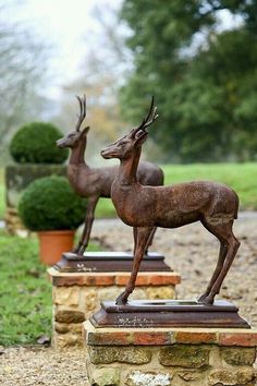 two statues of deer standing next to each other on top of a stone slab in the grass